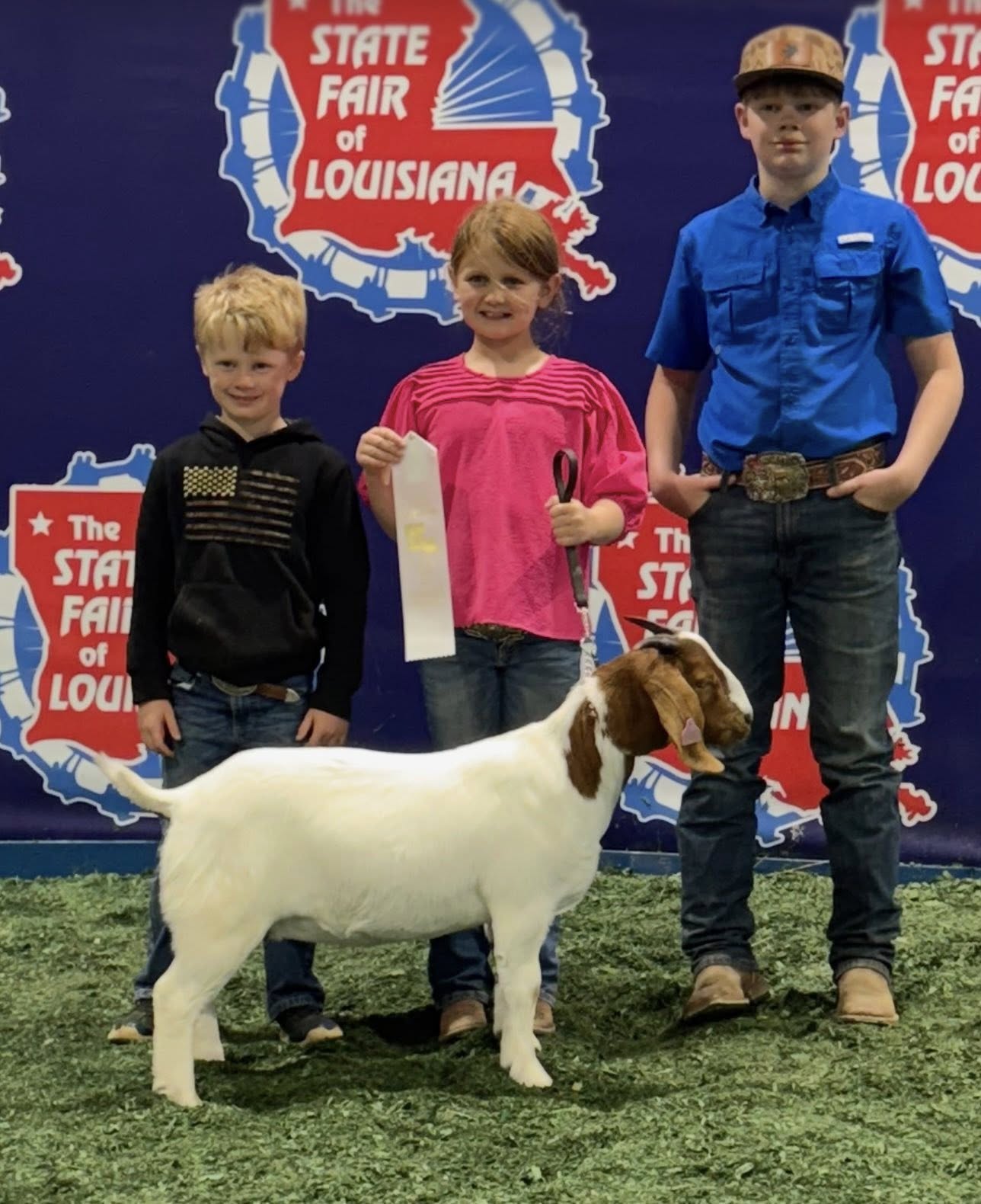 A girl and two boys with a white goat.